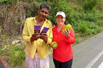 Equal Exchange Co-op farmer holds chocolate bars and cacao pods